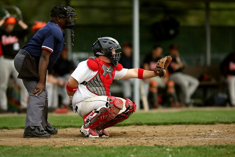 A baseball catcher and umpire in action during a game on a grassy field.