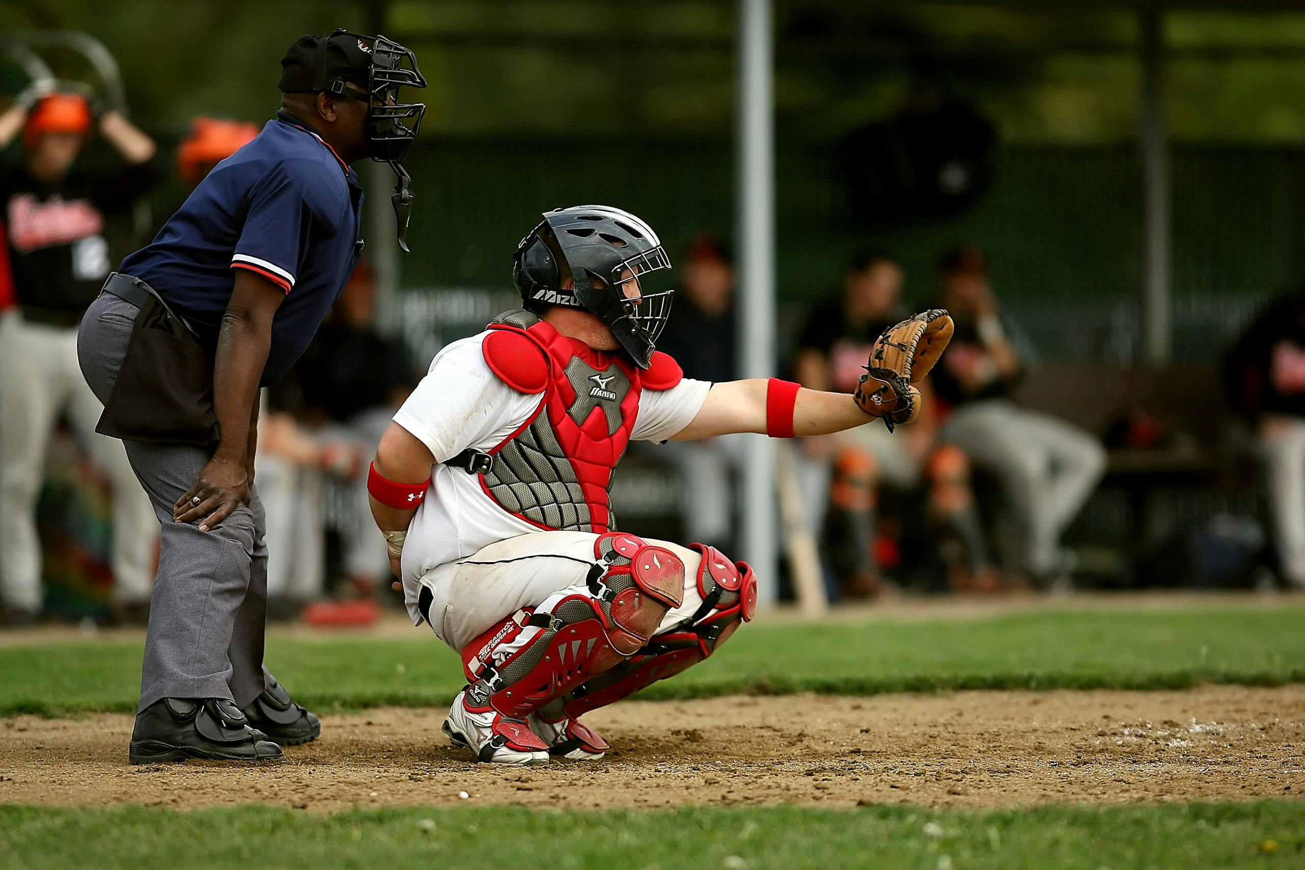 A baseball catcher and umpire in action during a game on a grassy field.