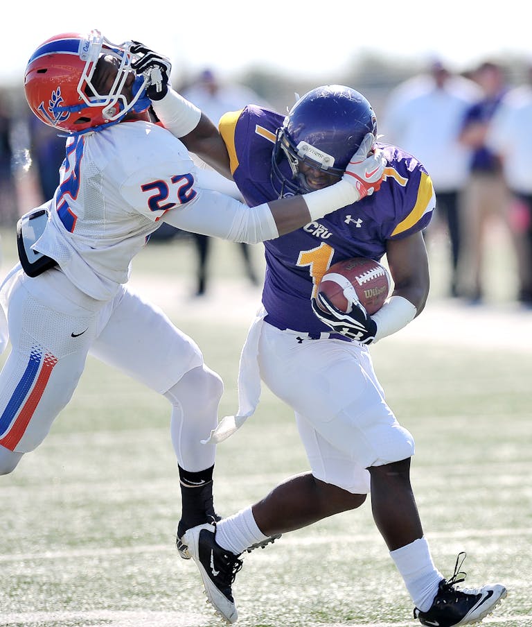 Dynamic action shot of American football players tackling during a competitive game outdoors.