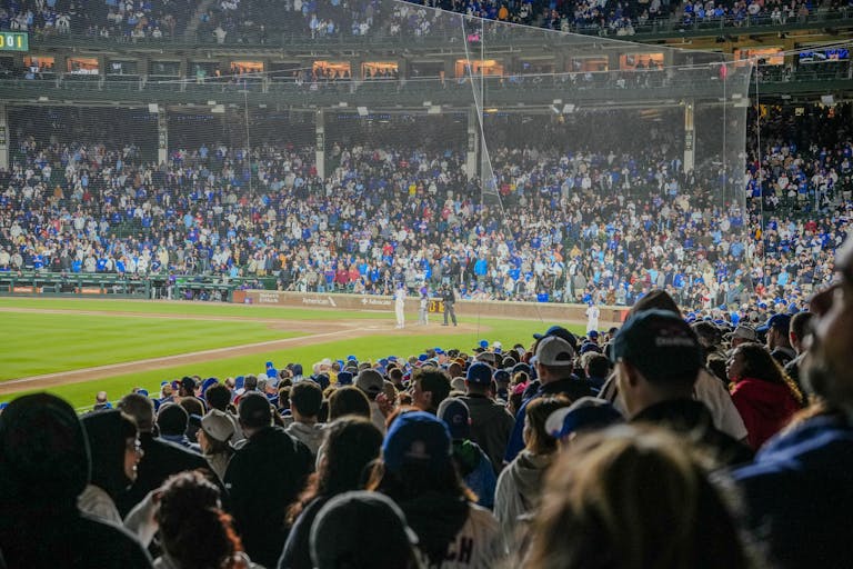 Energetic scene of a nighttime baseball game with a packed stadium crowd.
