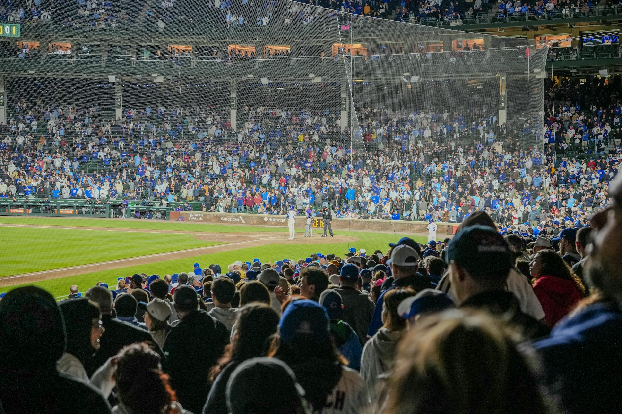 Energetic scene of a nighttime baseball game with a packed stadium crowd.