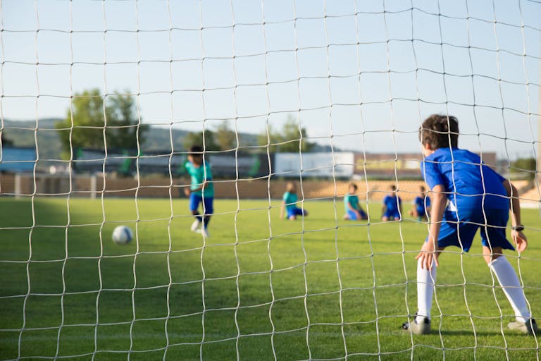 Kids enjoying a soccer match on a sunny day in Portugal with clear blue skies.