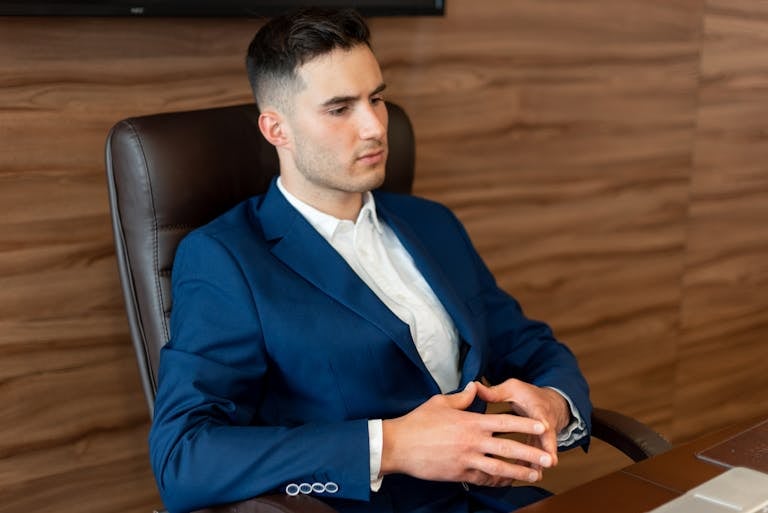 Professional man in a blue suit seated in an office, reflecting a focused business environment.