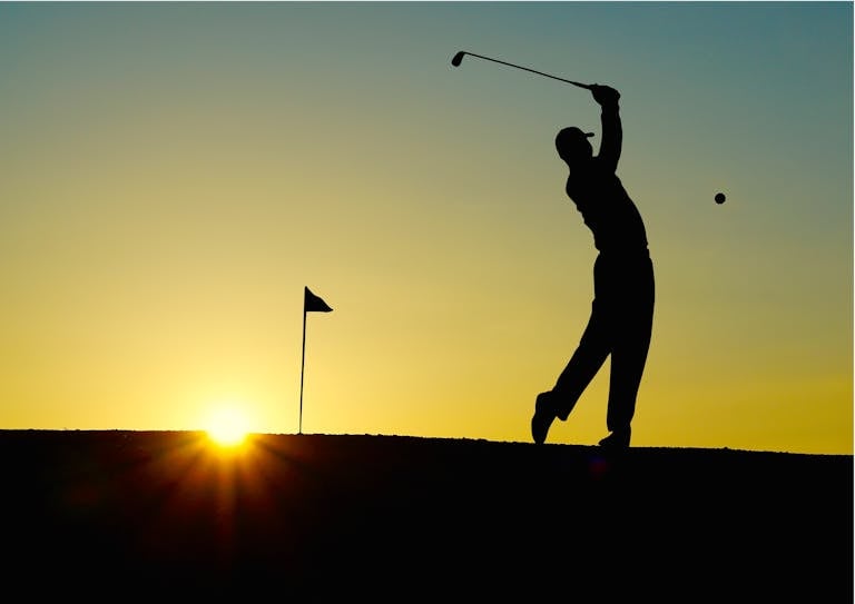 Silhouette of a golfer swinging at sunrise, capturing the essence of the sport.