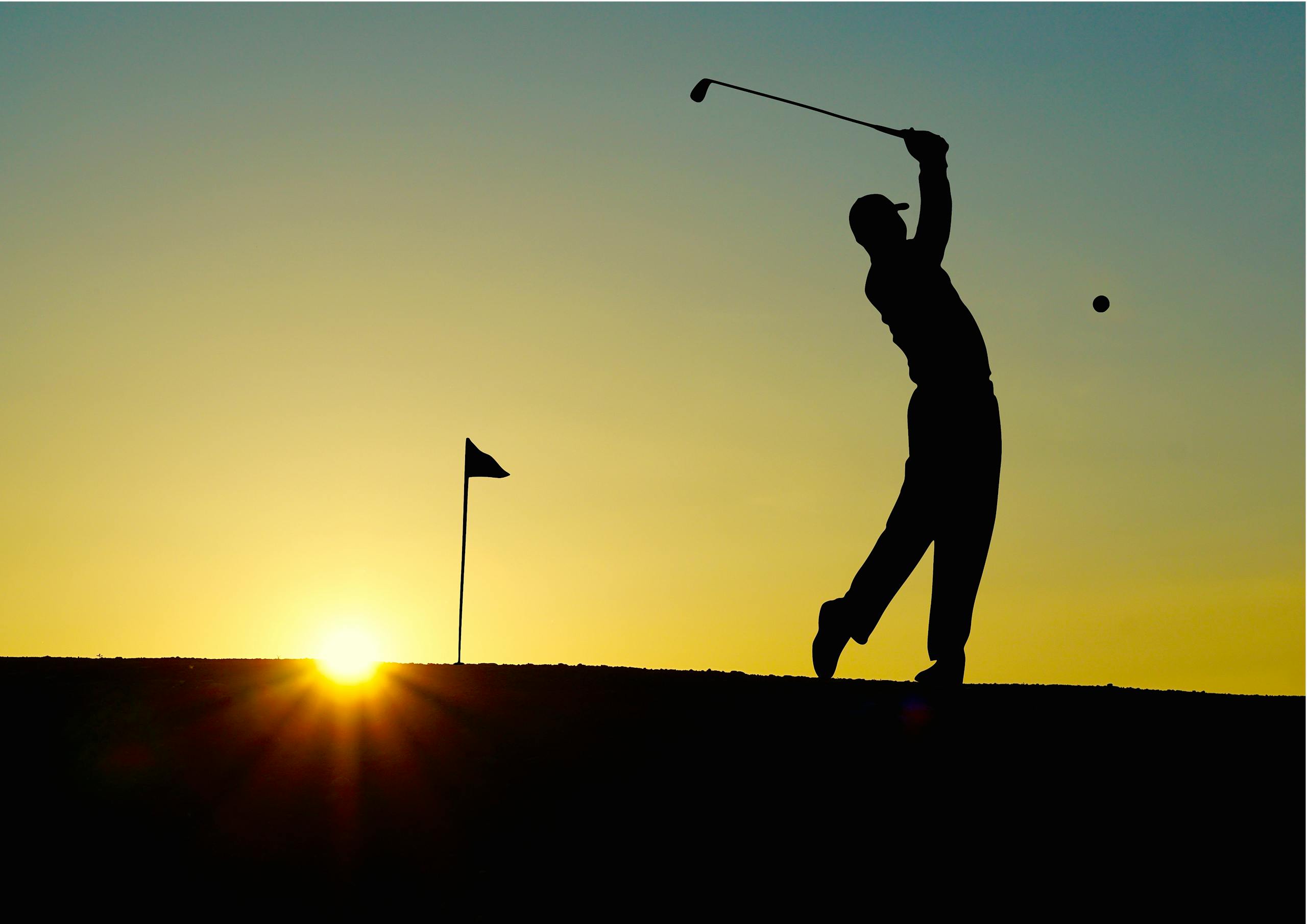 Silhouette of a golfer swinging at sunrise, capturing the essence of the sport.