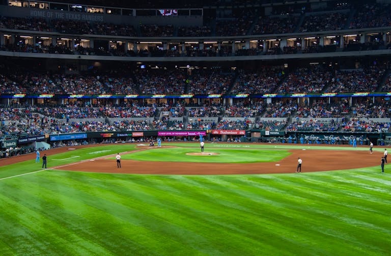 An engaging baseball game with a full crowd at Texas stadium under bright lights.
