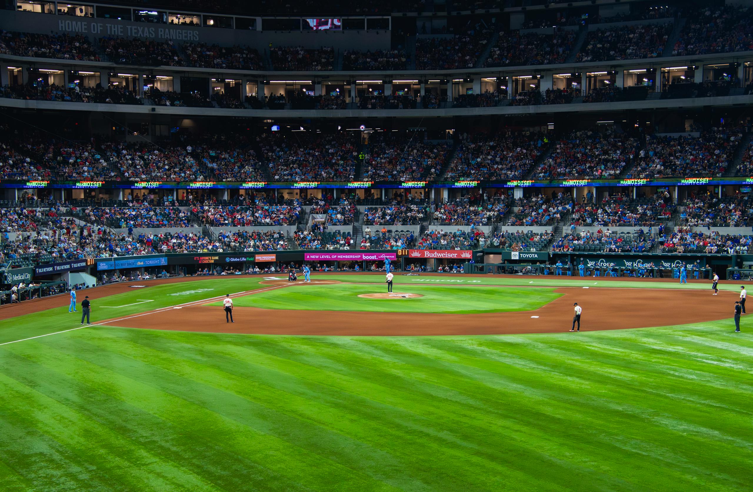 An engaging baseball game with a full crowd at Texas stadium under bright lights.