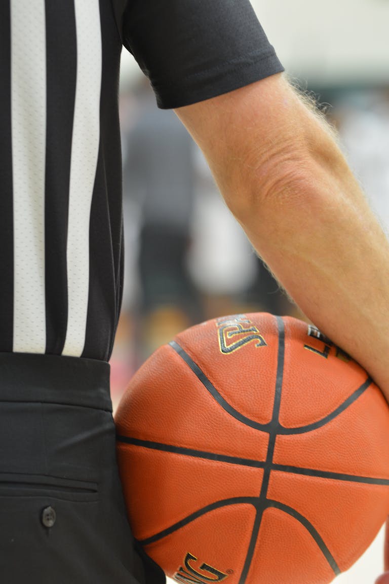 Close-up of a basketball referee holding a game ball during a match.