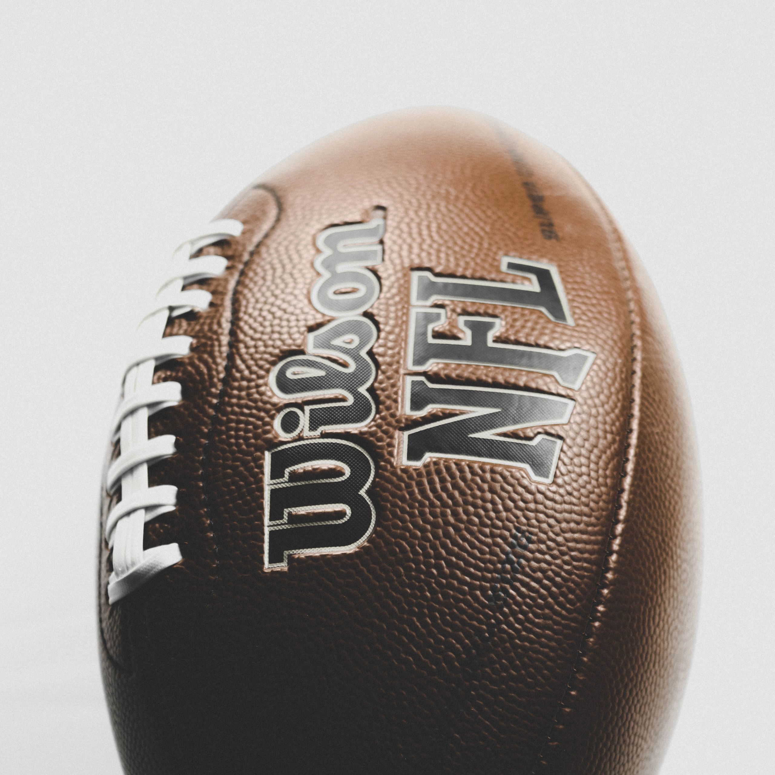Close-up of a Wilson NFL leather football captured in a studio setting, highlighting texture and branding.