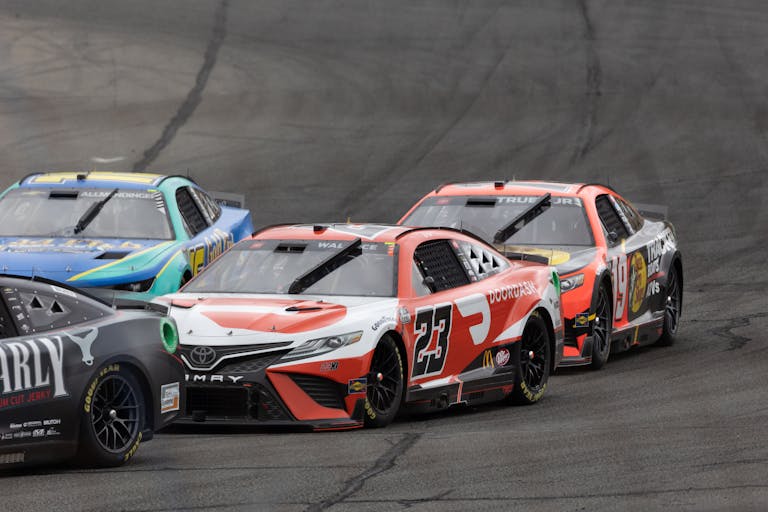 Dynamic image of stock cars racing closely on a track during a motorsport event.