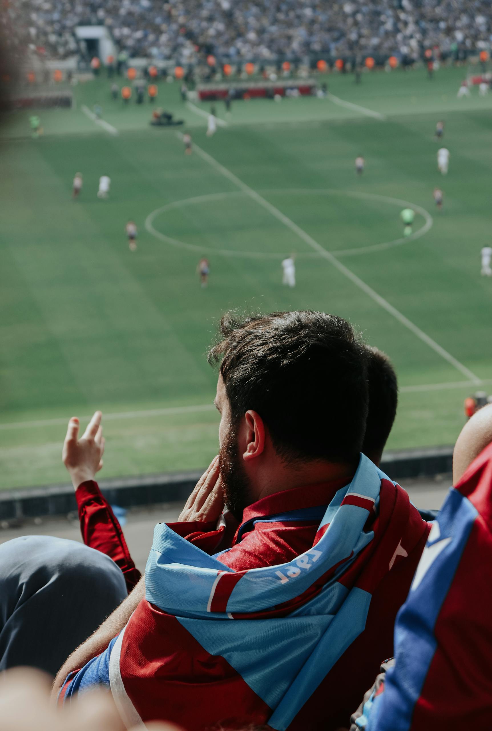Enthusiastic fan in sports jersey enjoys live football match in stadium.