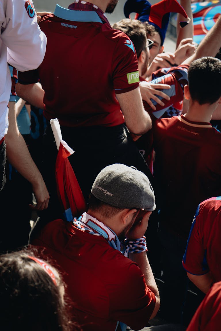 Enthusiastic group of fans cheering at an outdoor sports event on a sunny day.