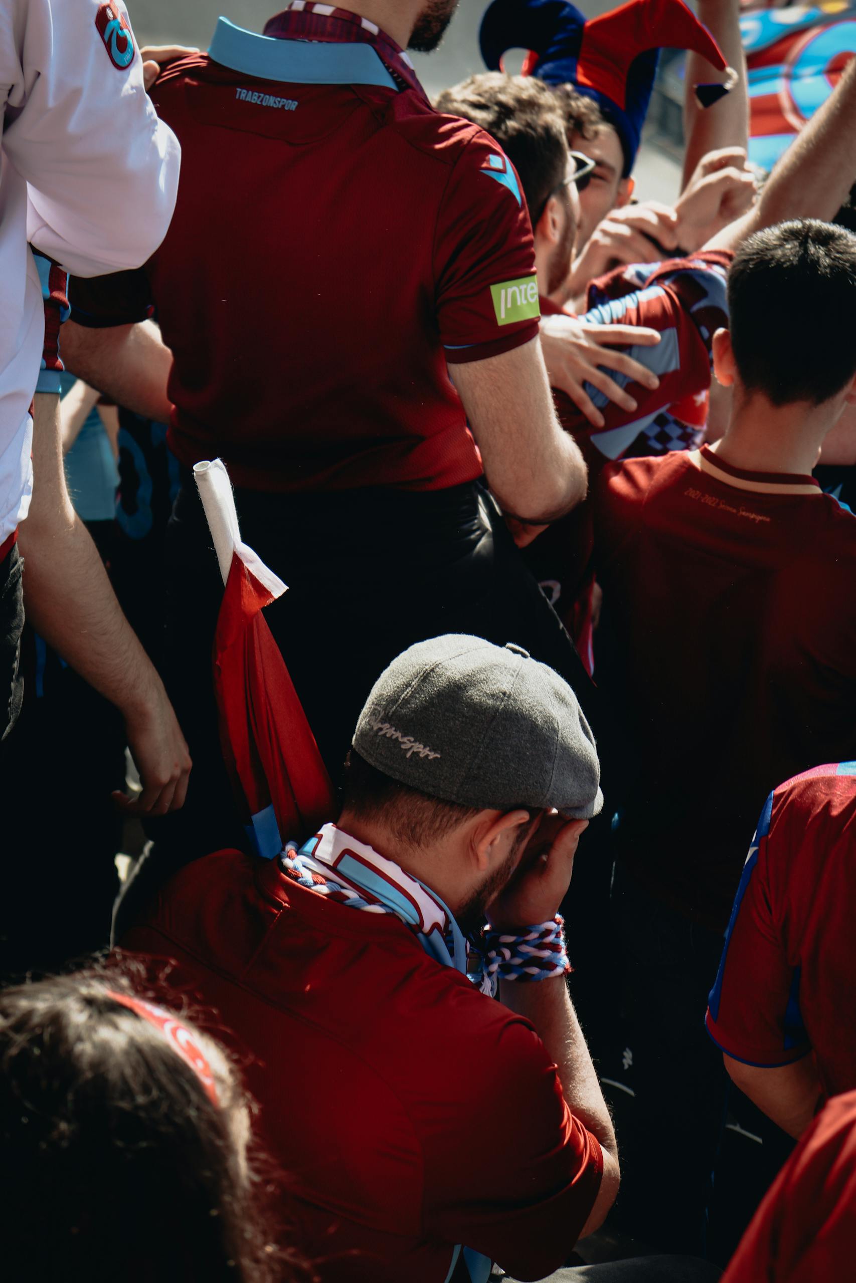Enthusiastic group of fans cheering at an outdoor sports event on a sunny day.