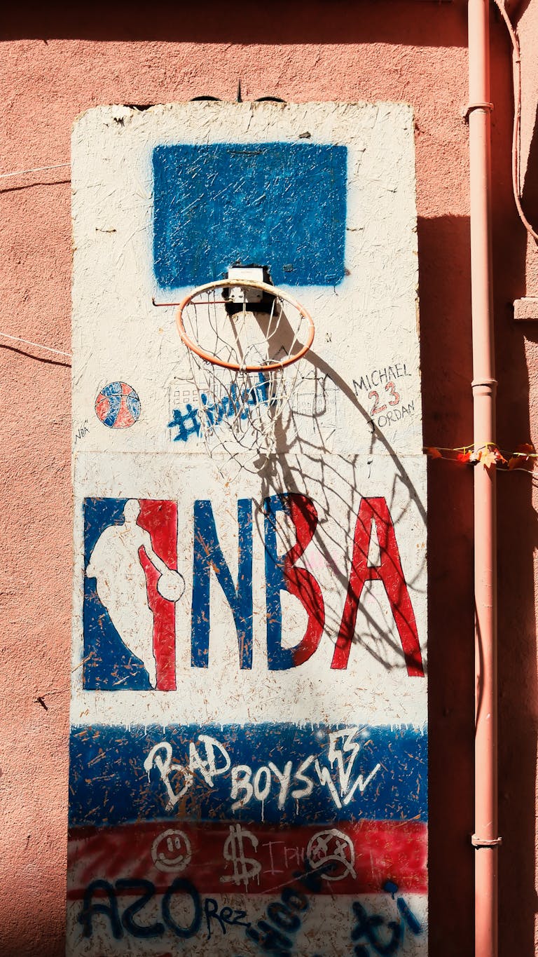 Graffiti-covered wall with a street basketball hoop, showcasing urban art style.