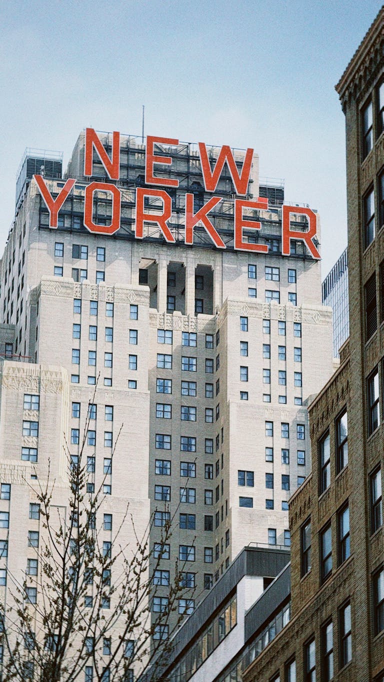 Iconic New Yorker Hotel sign against a clear urban skyline.