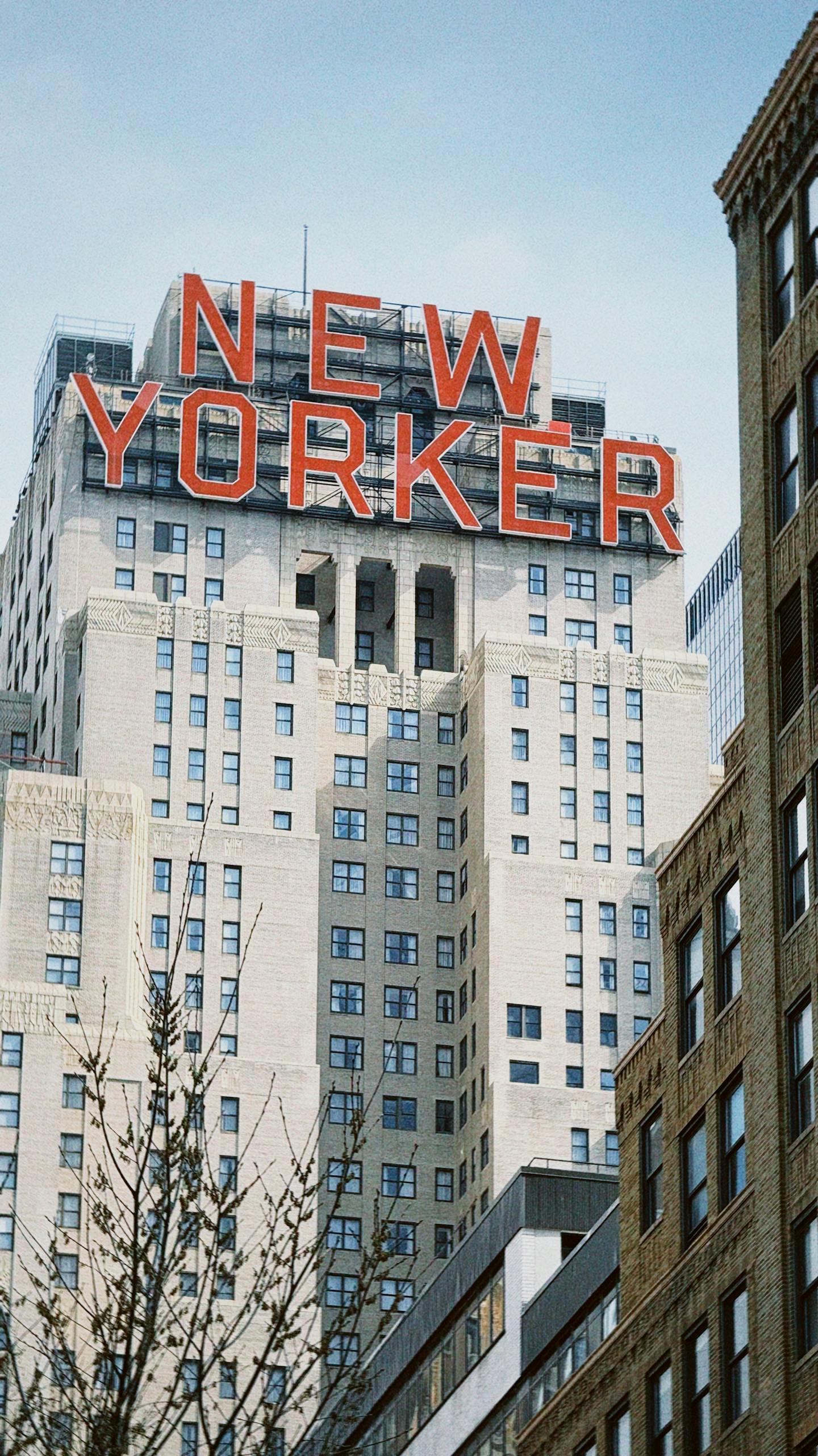 Iconic New Yorker Hotel sign against a clear urban skyline.