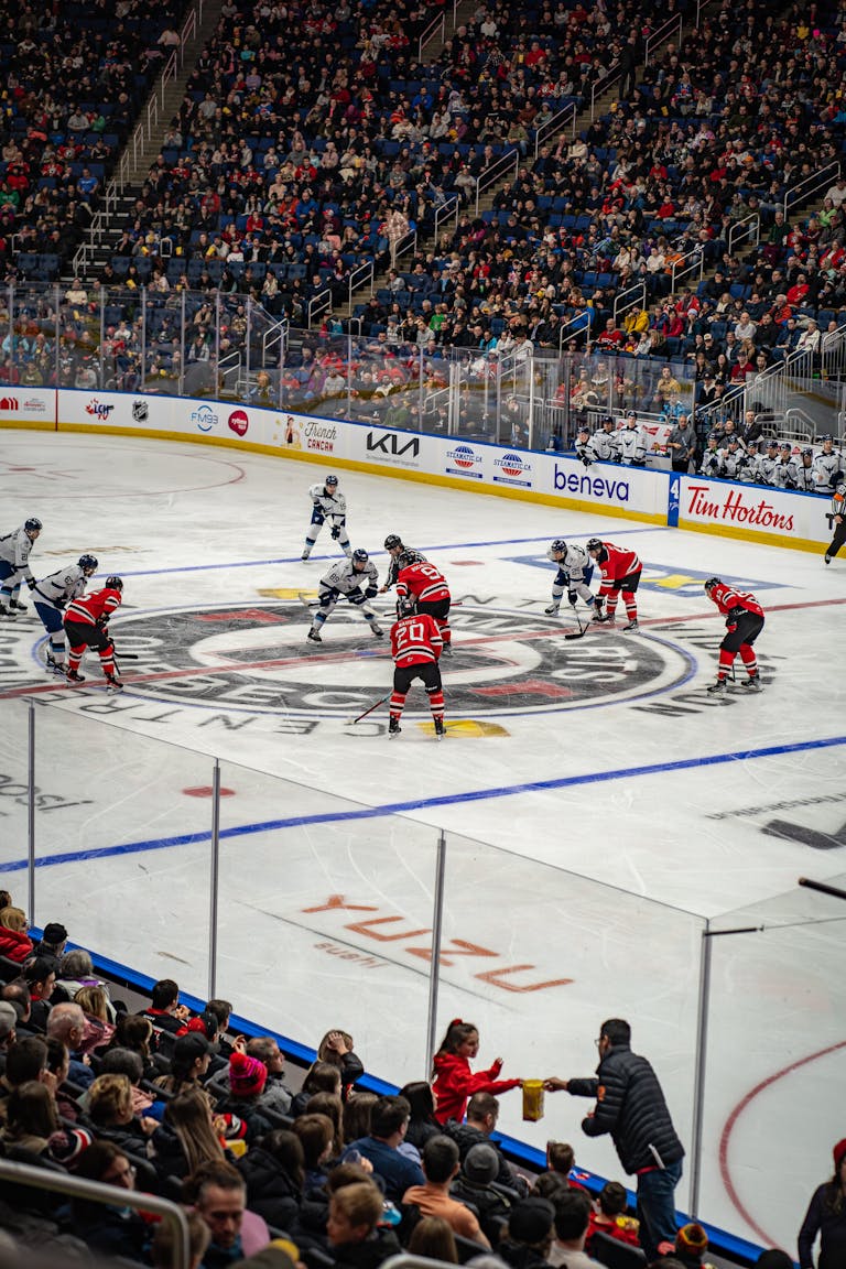 Intense hockey face-off amidst cheering crowd in Québec's vibrant stadium, showcasing sports energy.