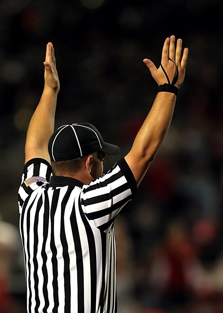 Referee raising hands to signal a goal or touchdown in a match.