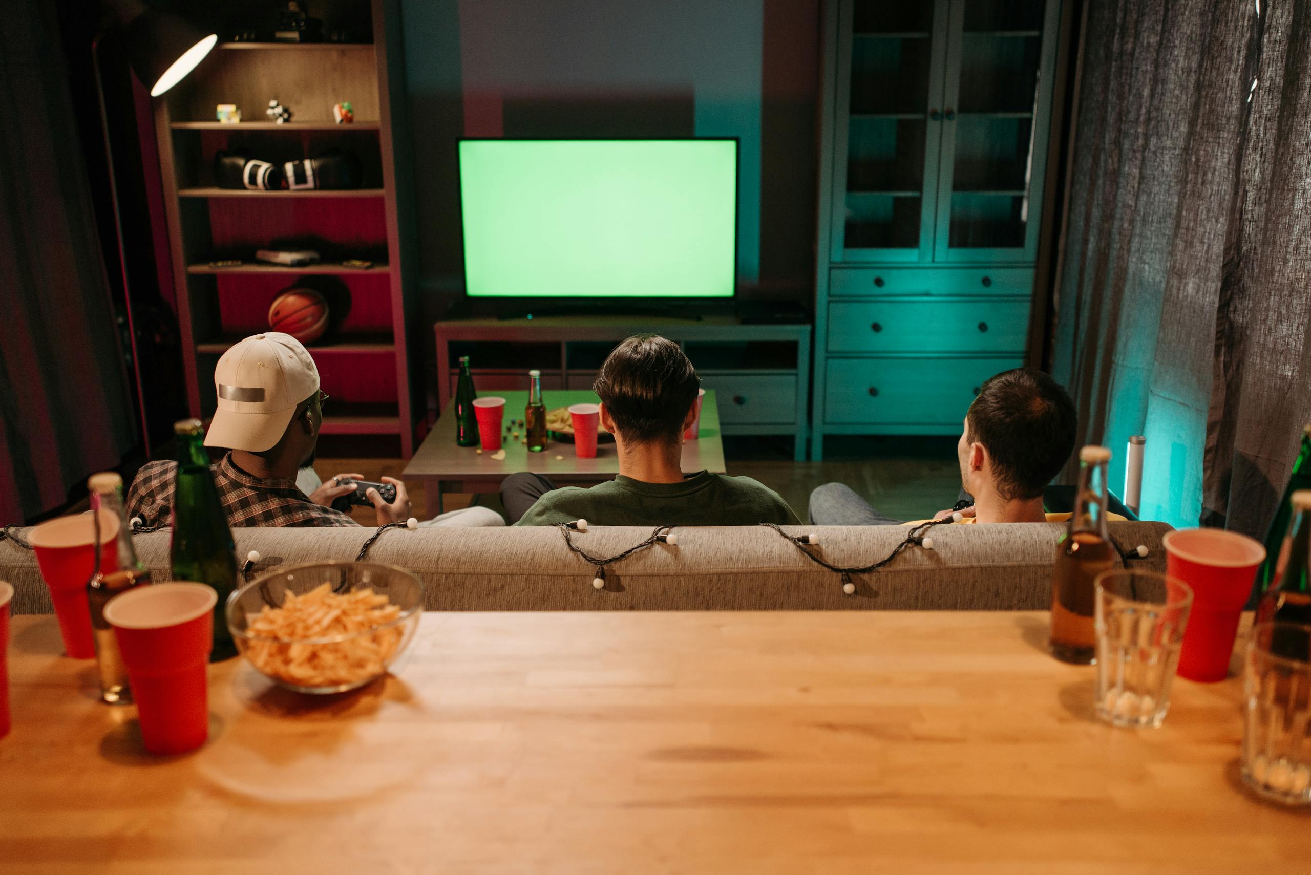 Three friends sitting on a couch playing video games together in a cozy living room setting.