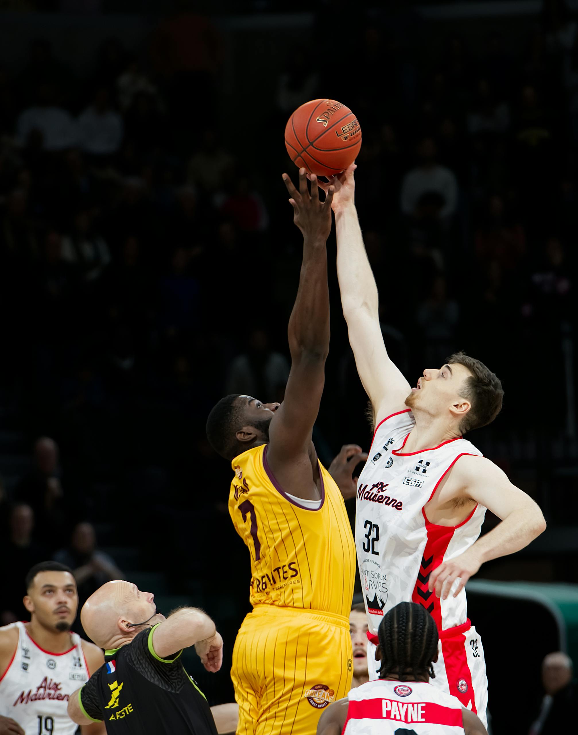 Two basketball players jump for the ball at the start of a thrilling game.