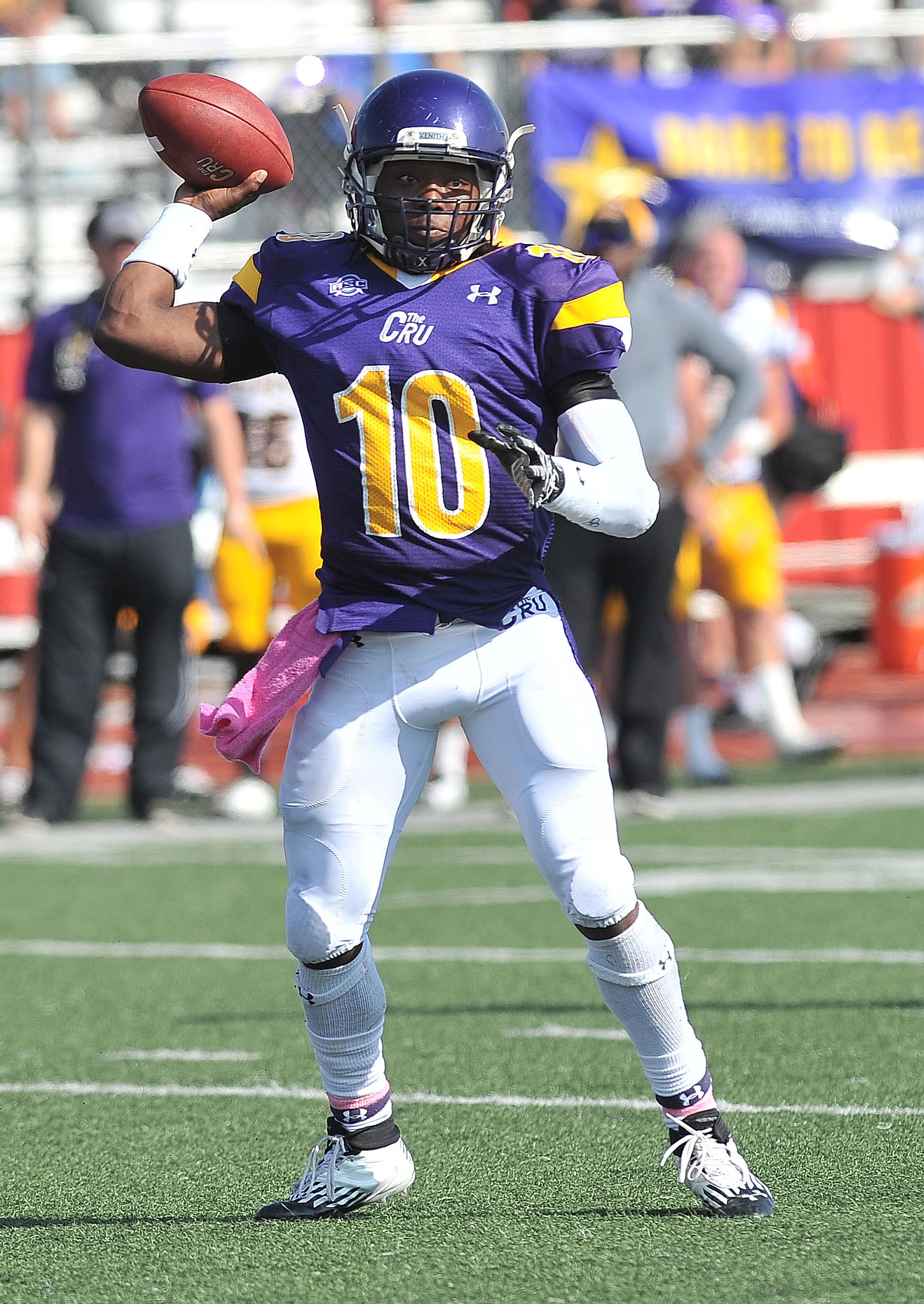 A football player in uniform executing a powerful throw during a game on a sunny day.