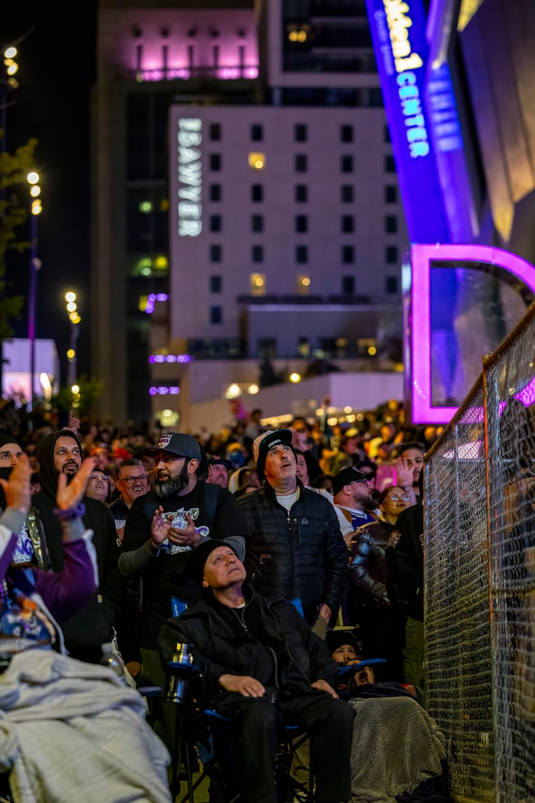 A large crowd gathered outdoors at night in Denver, enjoying a public event with vibrant lights.