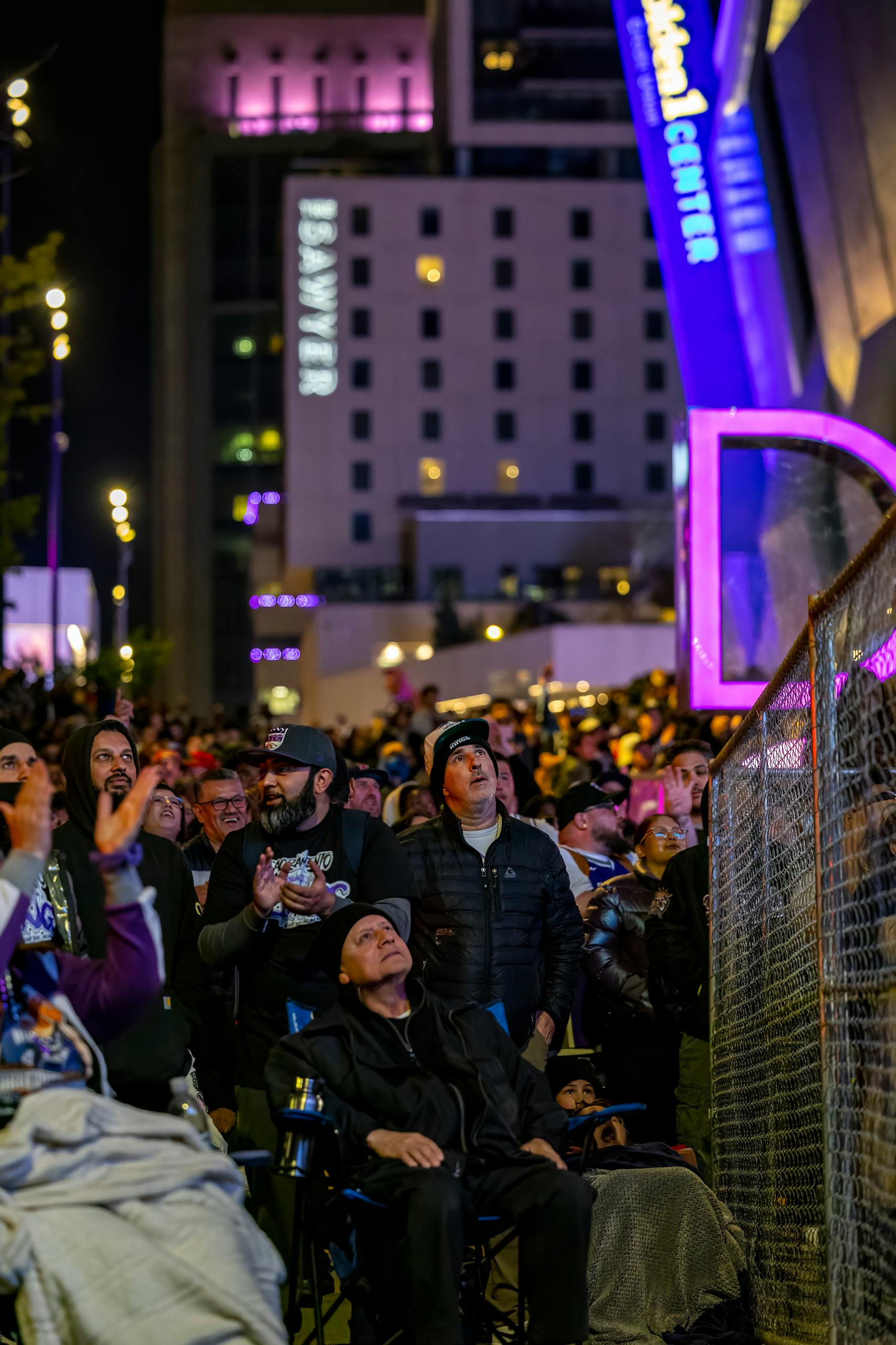 A large crowd gathered outdoors at night in Denver, enjoying a public event with vibrant lights.