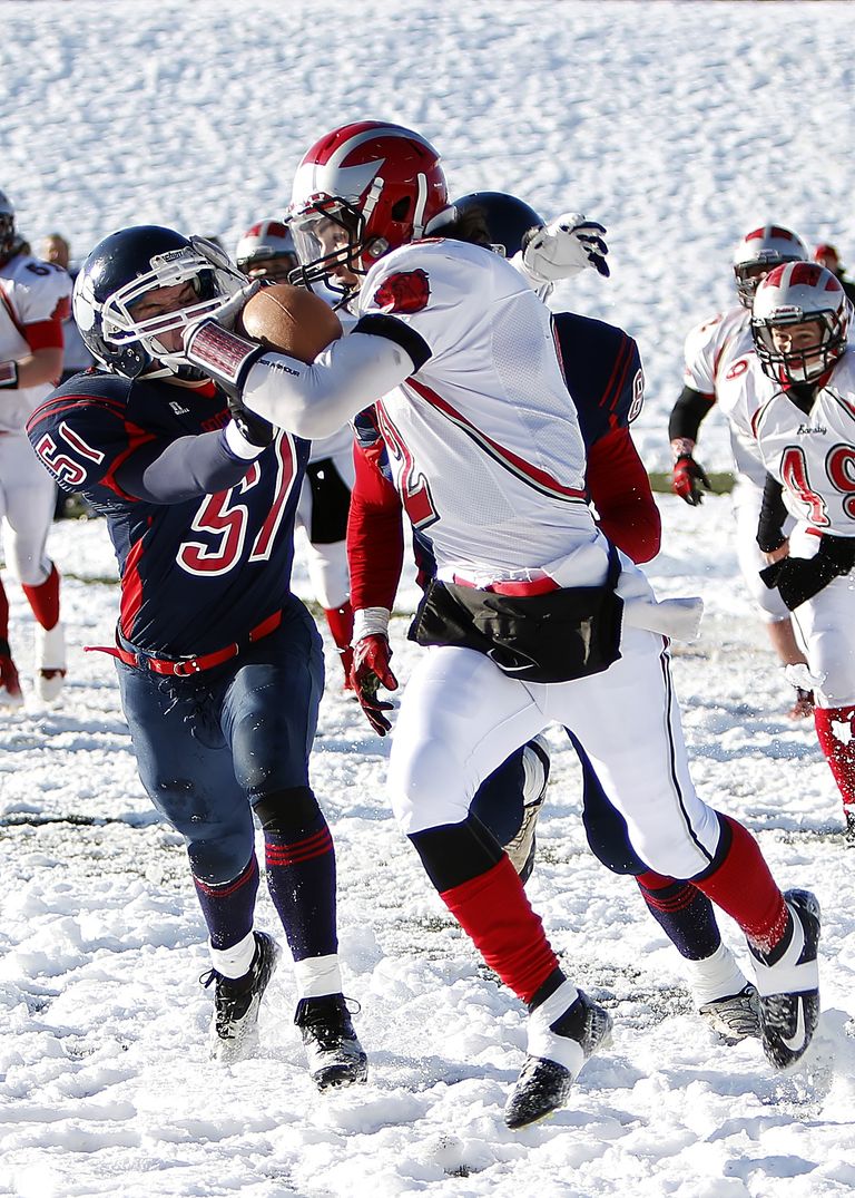 Action-packed American football match in winter snow, showcasing athlete's energy and determination.