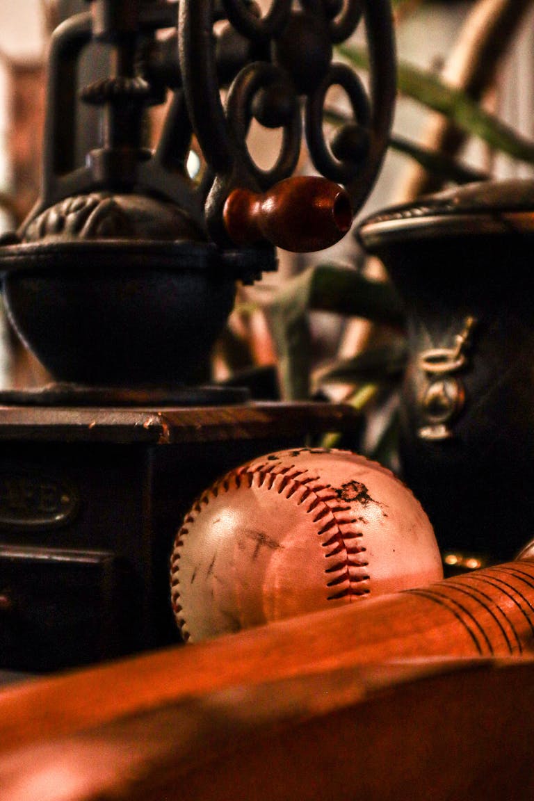 An artistic still life featuring a vintage coffee grinder and a baseball with a bat.