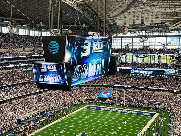 An exciting football game is underway at the AT&T Stadium in Arlington, Texas, with a packed crowd and dynamic atmosphere.