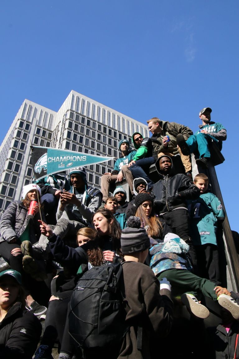 Crowd celebrating in Philadelphia with a city building backdrop and a team flag.