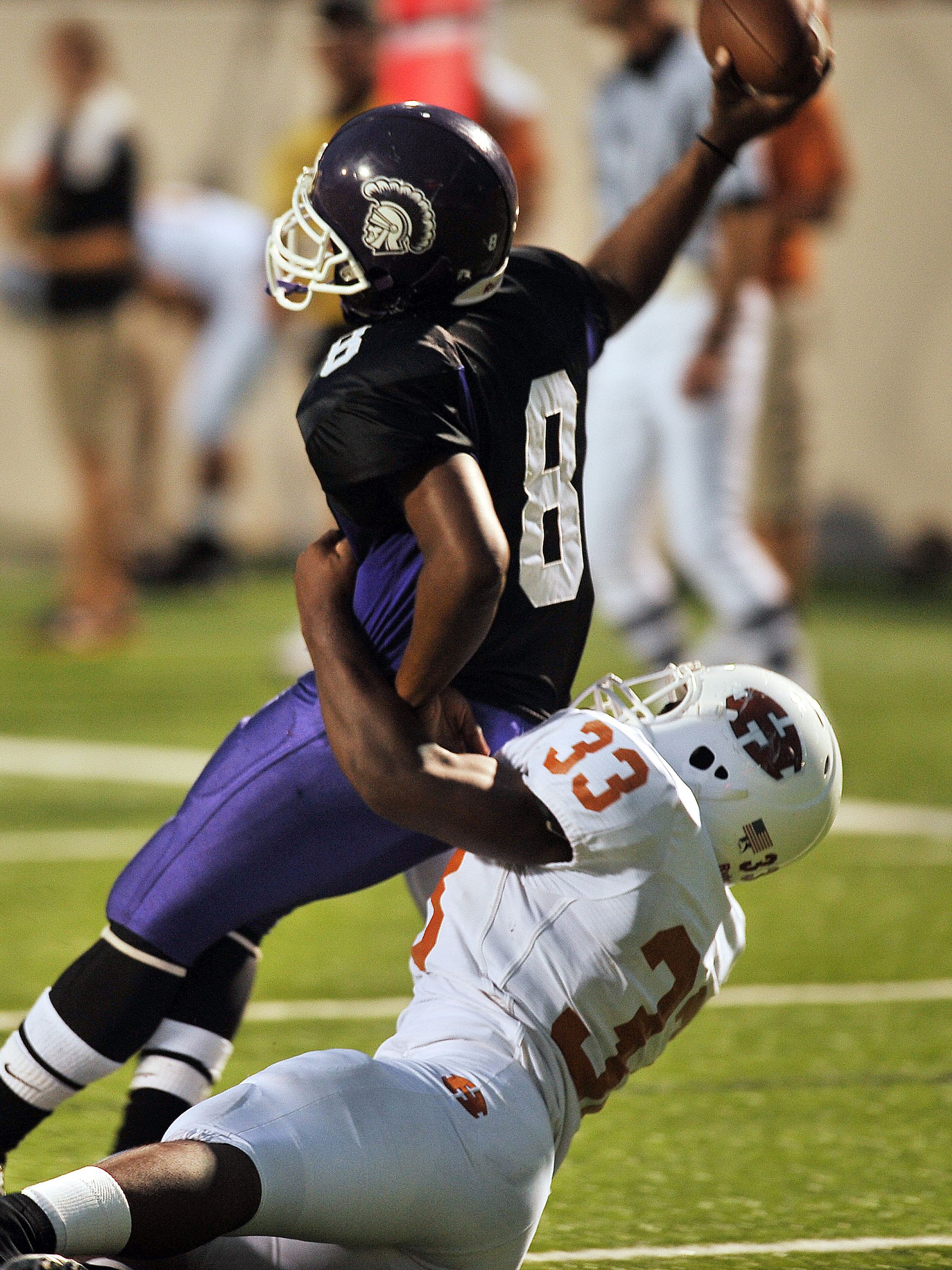 Dynamic action scene of a tackle during an American football game. Players in full gear compete on the field.