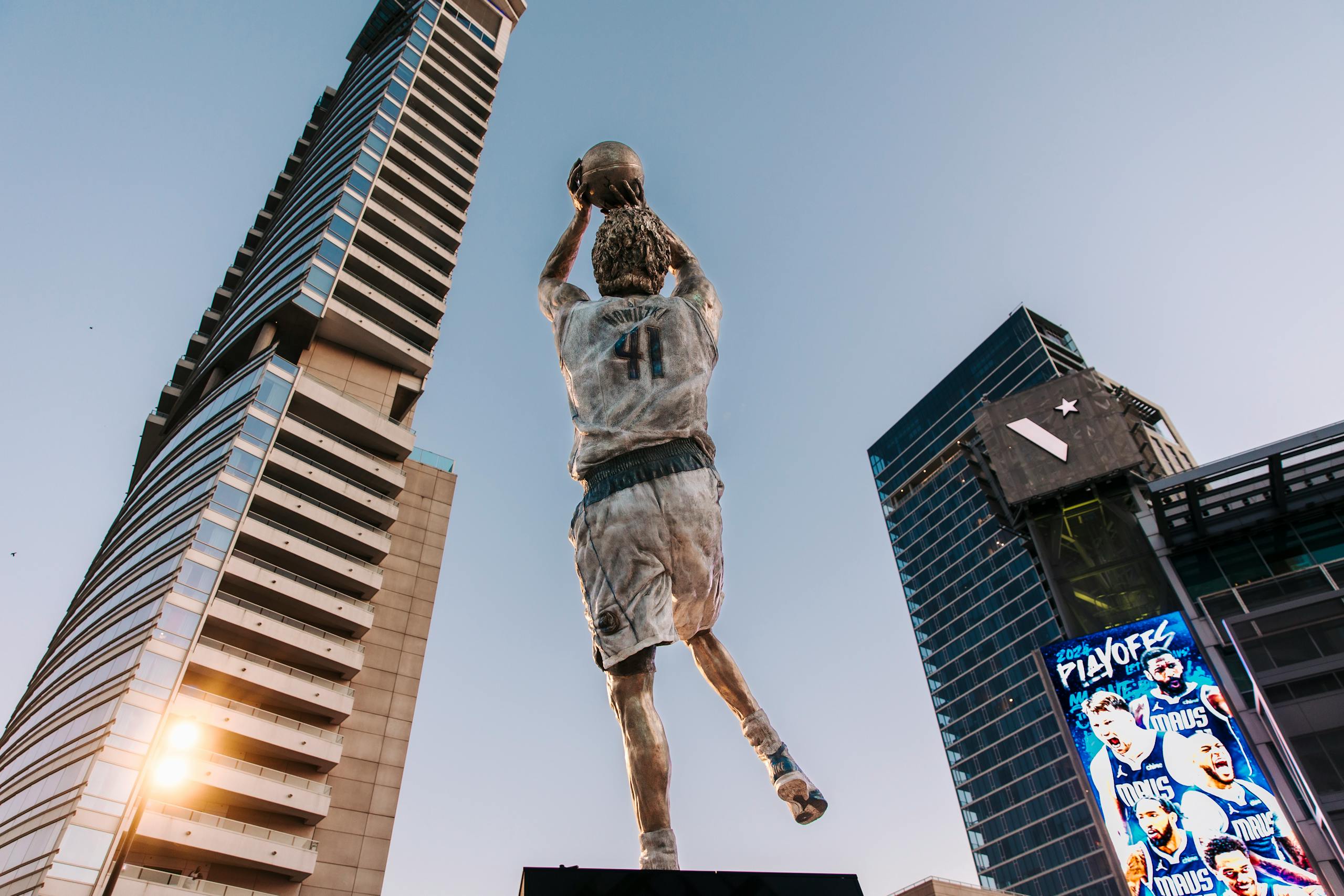 Dynamic statue with basketball skyscraper backdrop showcasing urban architecture.