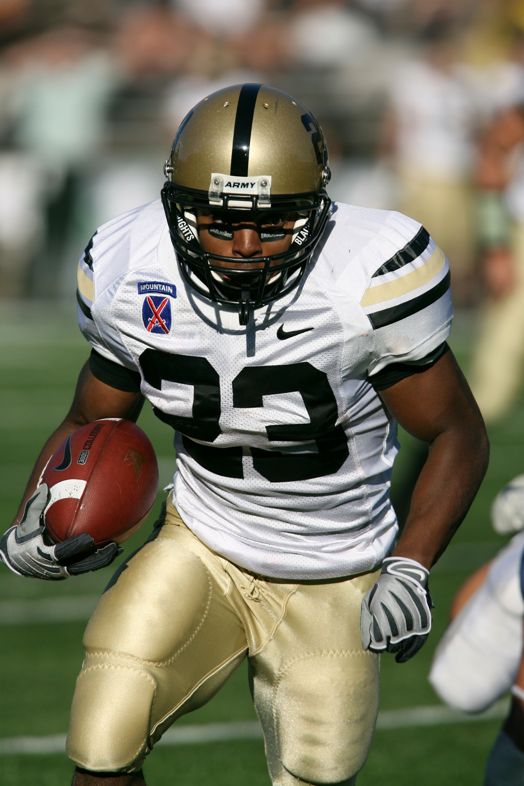 Focused American football player running with ball during game.