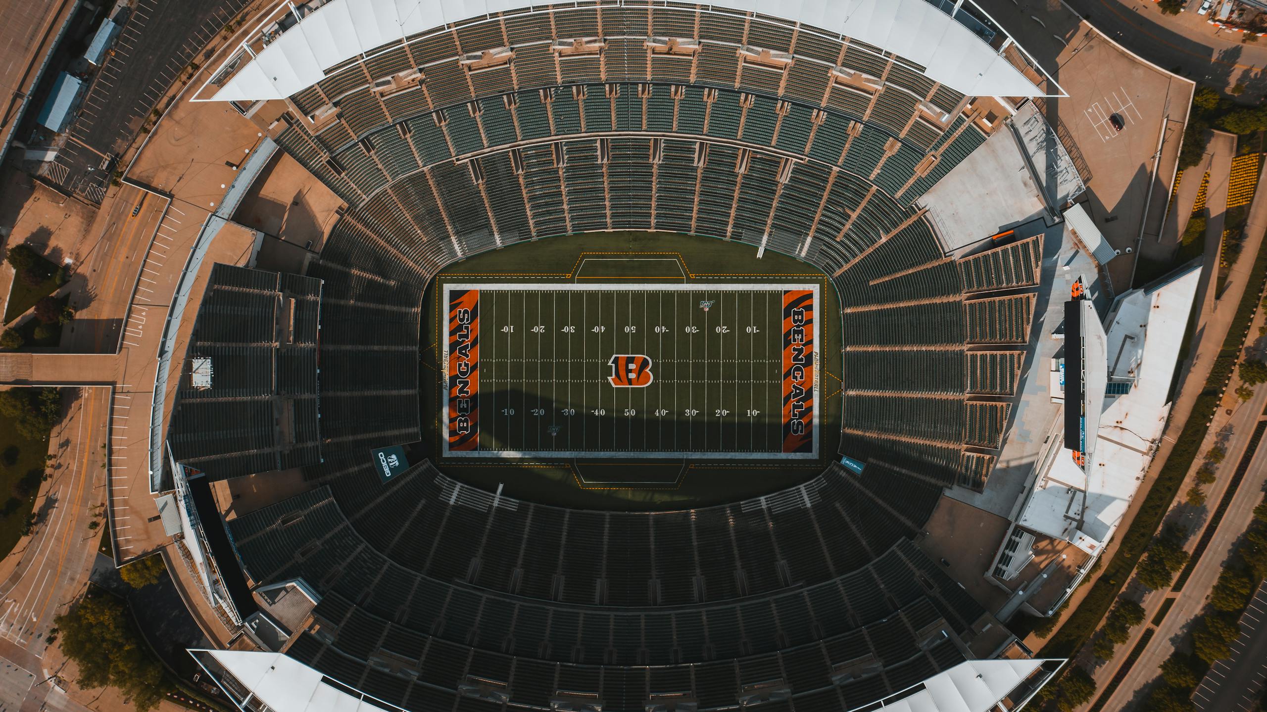 From above drone view of empty American football stadium with white lines and emblem on sunny day