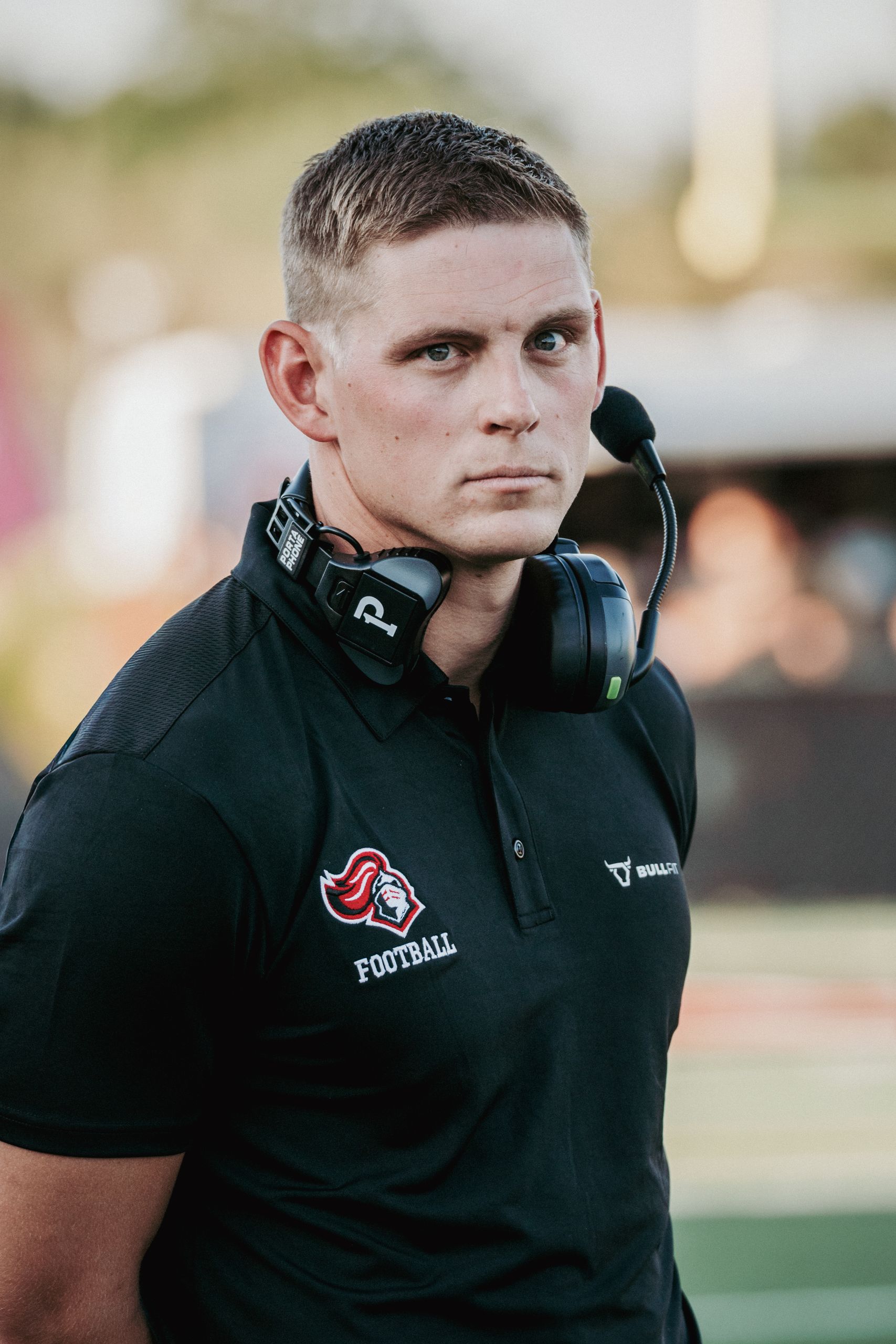 Portrait of a dedicated high school football coach exuding intense focus and determination outdoors.