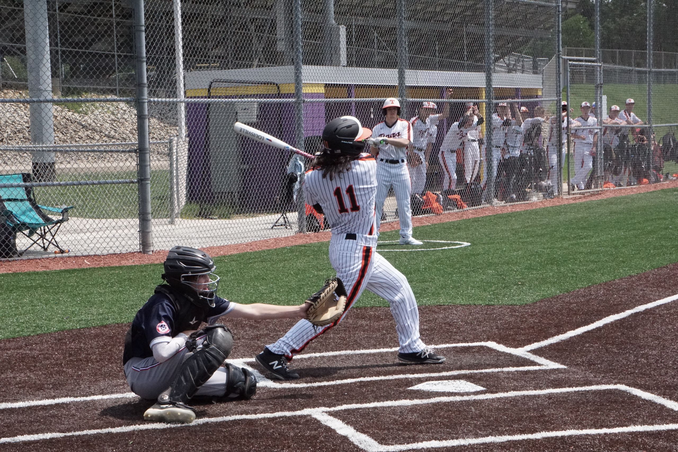 A dynamic scene of a baseball game with a batter swinging at the ball while the catcher is ready. Perfect sports shot.