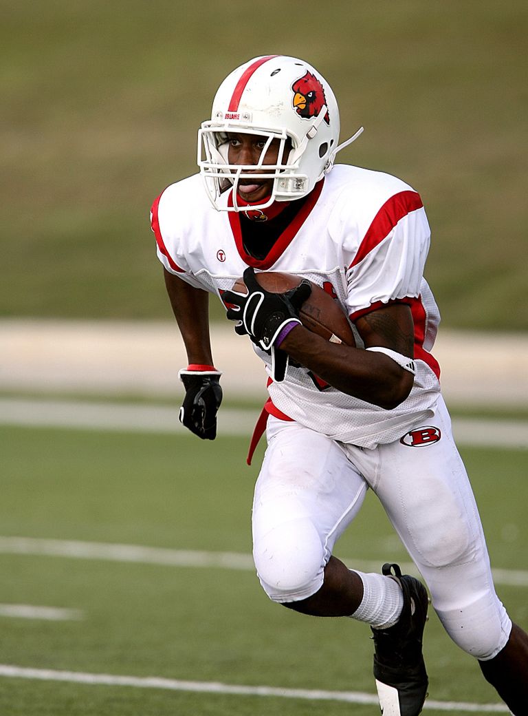 A football player in uniform running on the field during a game, showcasing athleticism and focus.