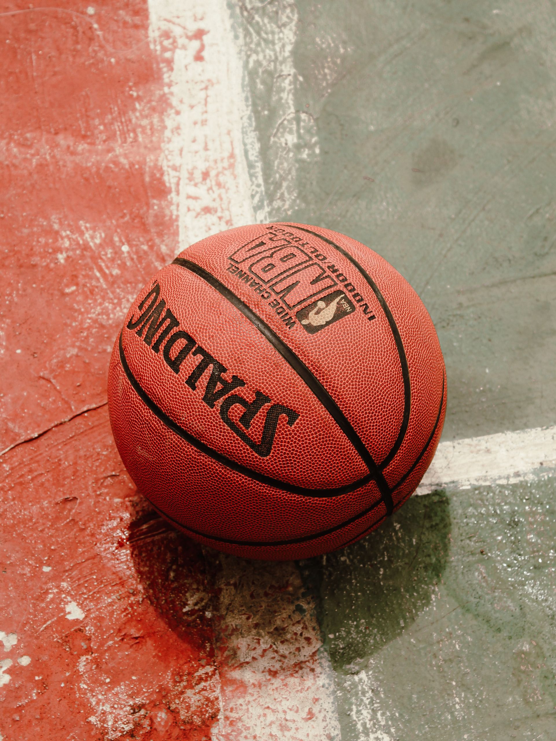A Spalding basketball on a colorful outdoor street court, showcasing vibrant sports culture.
