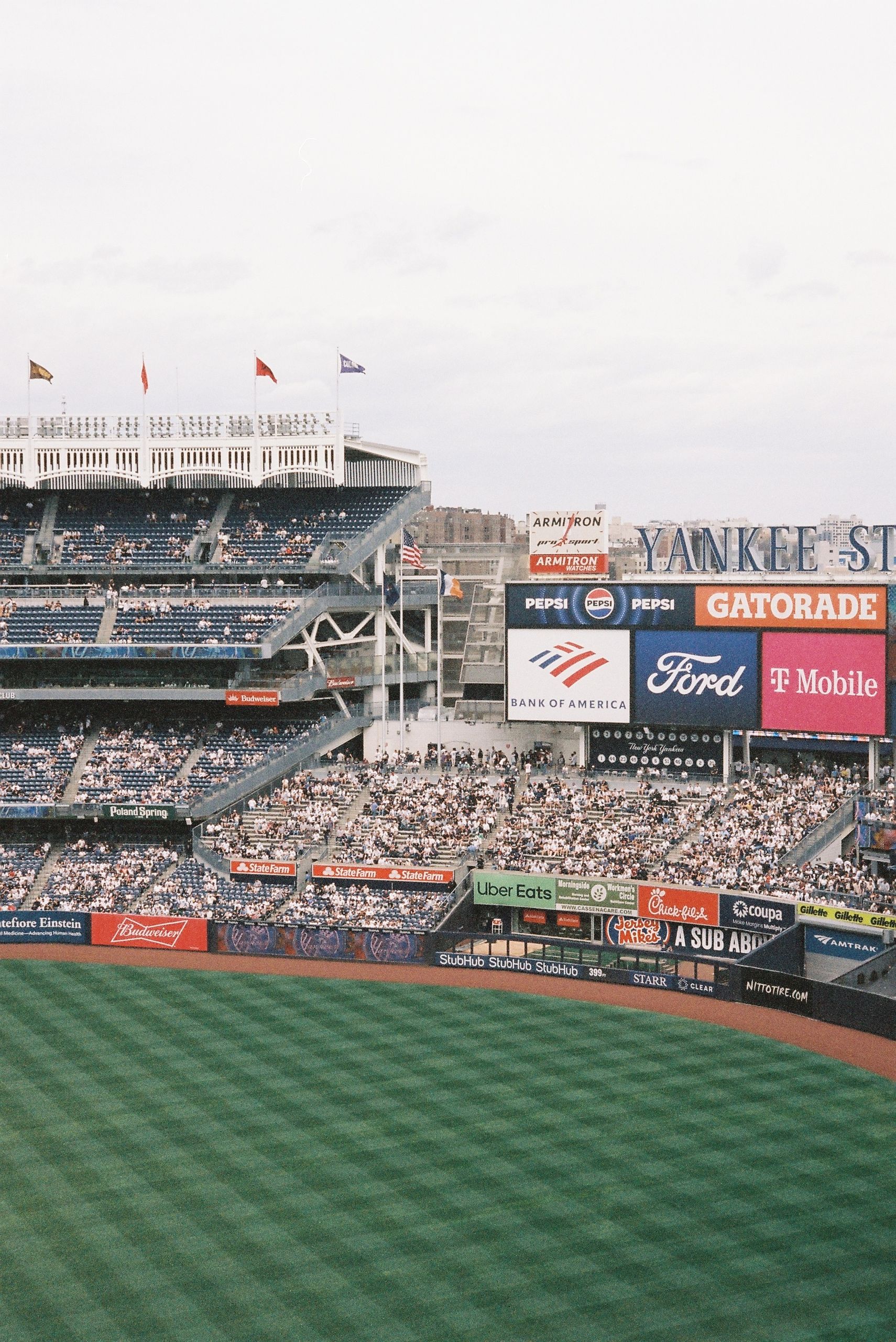 A vibrant daytime scene of Yankee Stadium filled with spectators and vibrant signage.