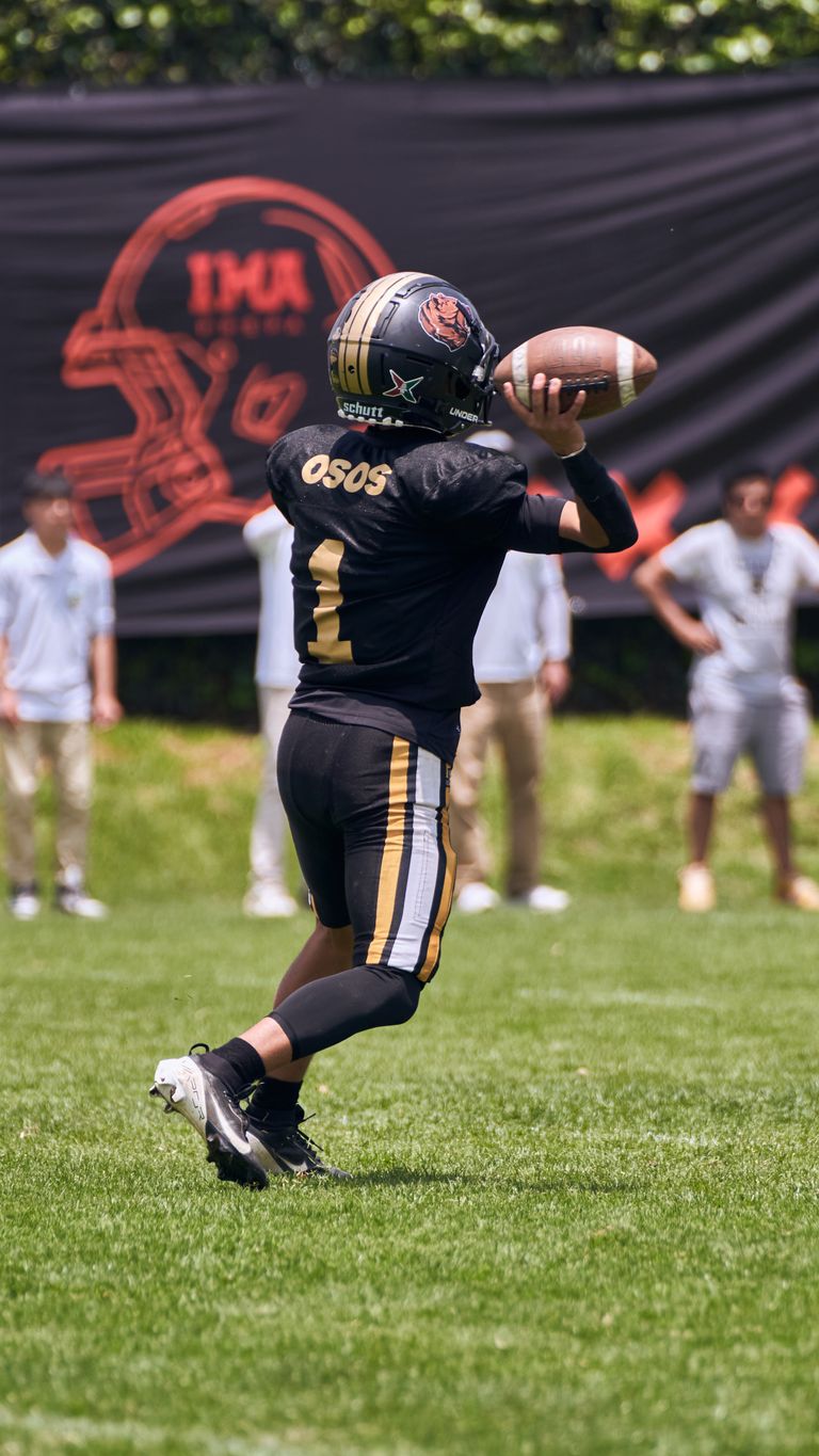 A young quarterback throws a football during a sunny outdoor game.