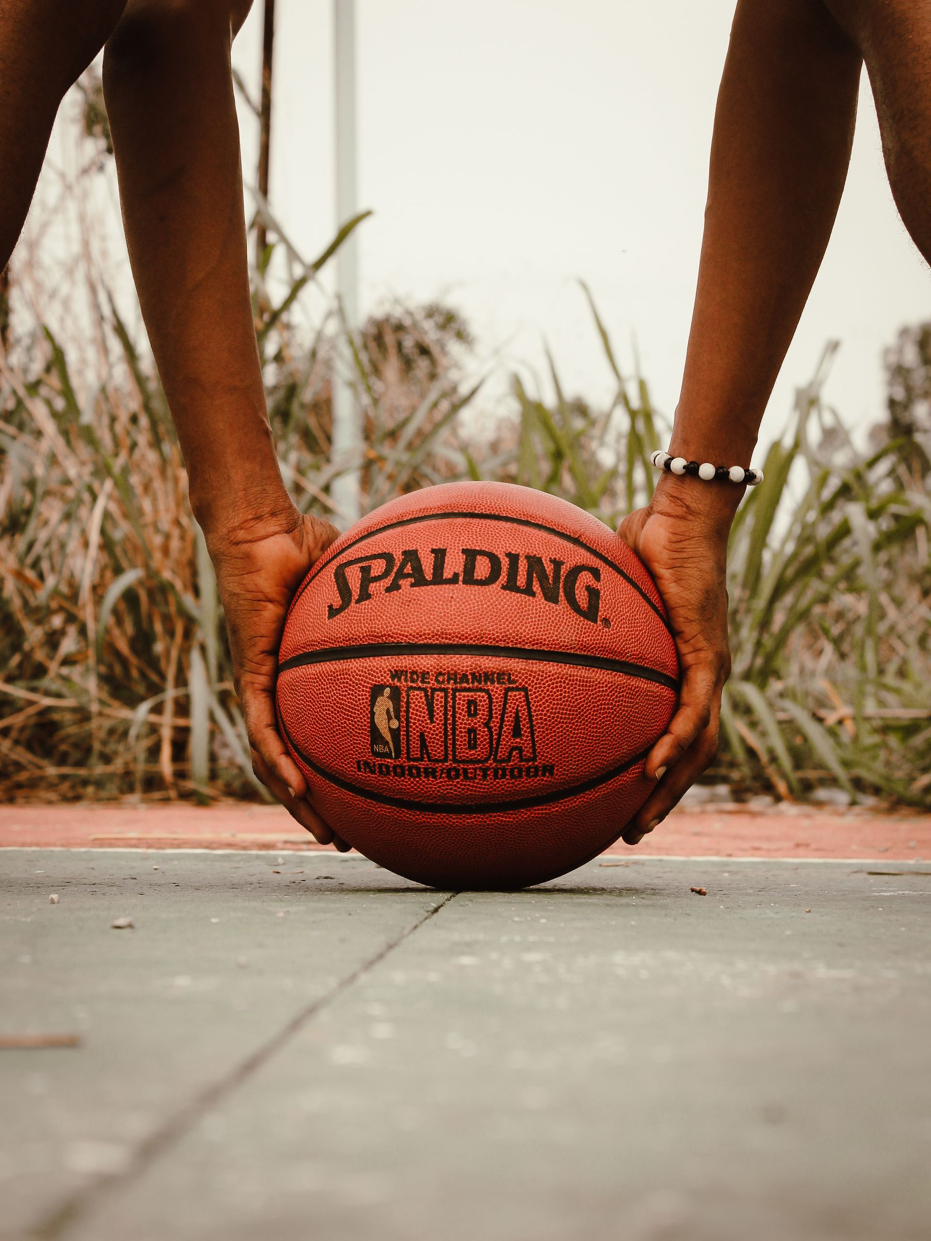 Capturing the intensity of basketball with close-up hands on Spalding ball outdoors.