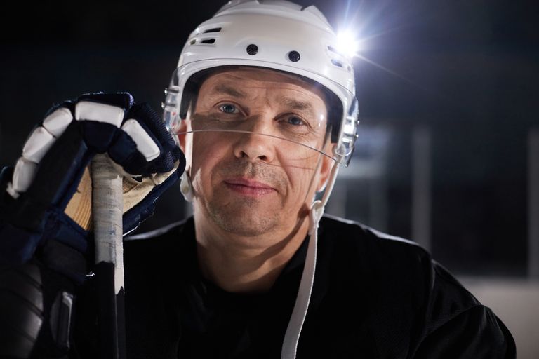 Close-up portrait of a mature male ice hockey player wearing full gear on the rink.
