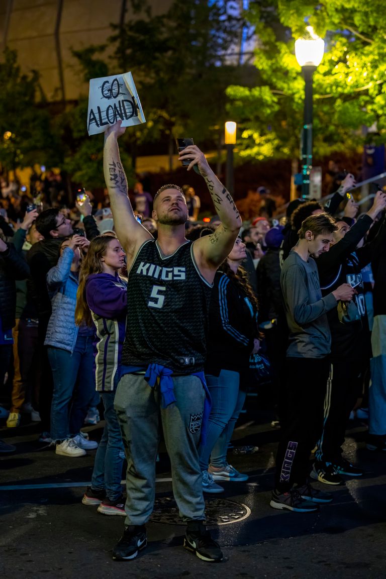Crowd gathers to support basketball team during a vibrant evening street celebration.