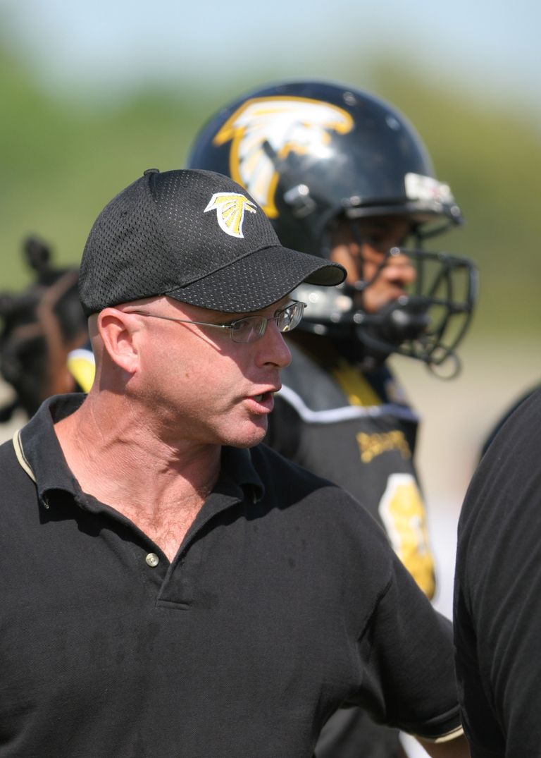 Football coach passionately motivating his team during a game.
