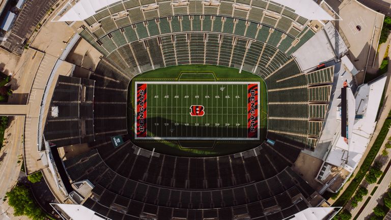 Top view of empty tribunes and American football stadium with white lines and emblem on sunny day