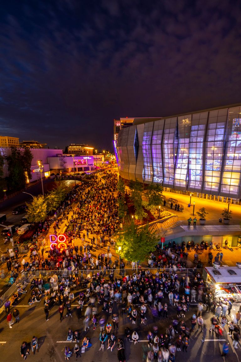 Vibrant night street festival with crowd and illuminated modern architecture.
