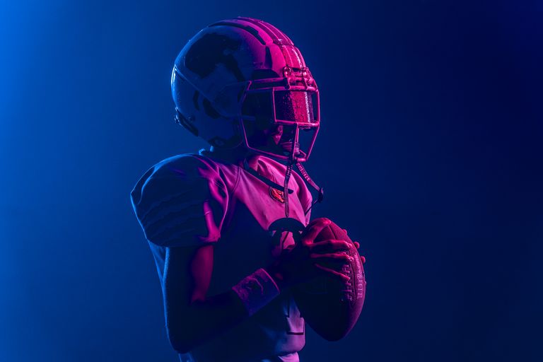 Young athlete in football gear with bold lighting for a dramatic effect.