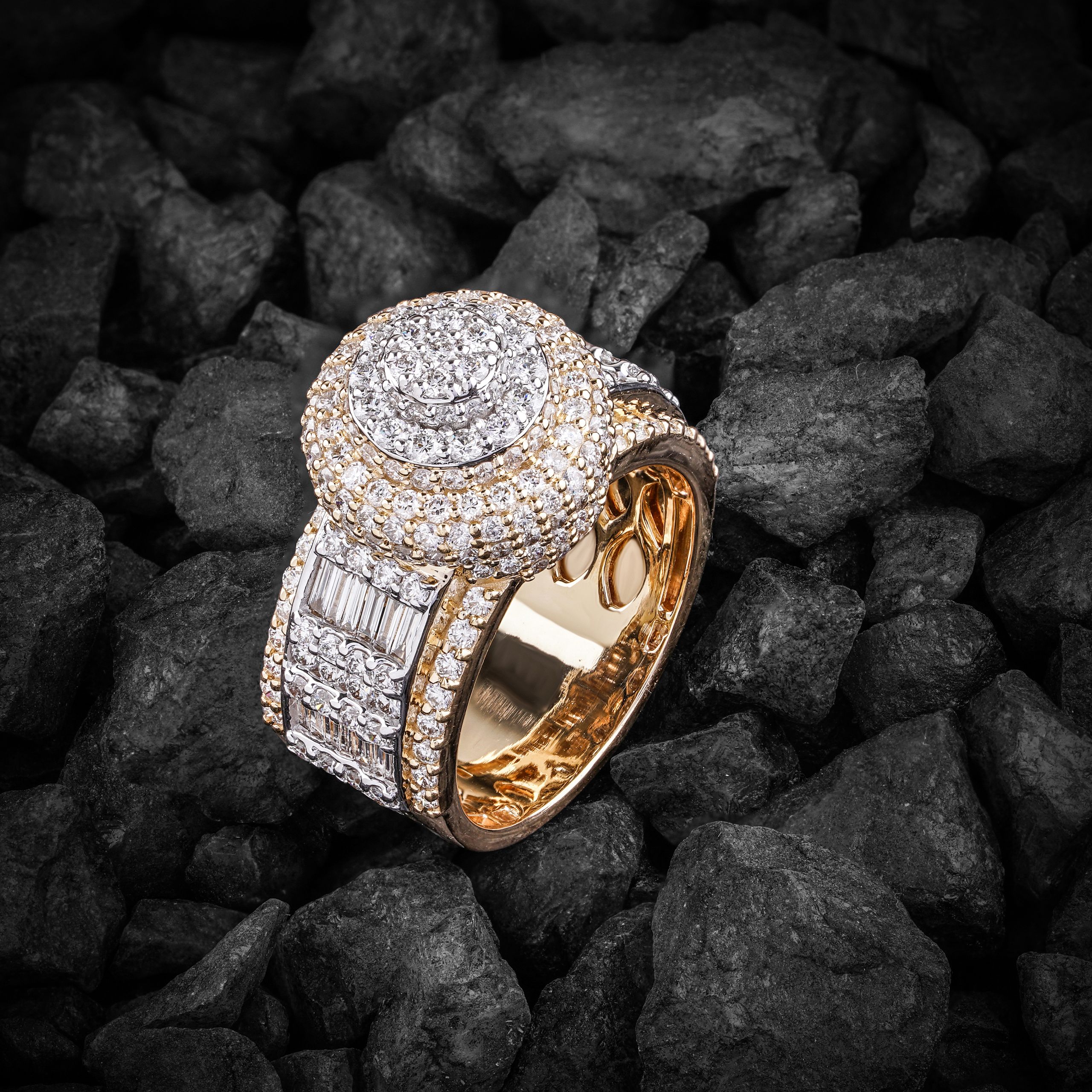 Close-up of an elegant diamond ring placed on textured black stones, exuding opulence.