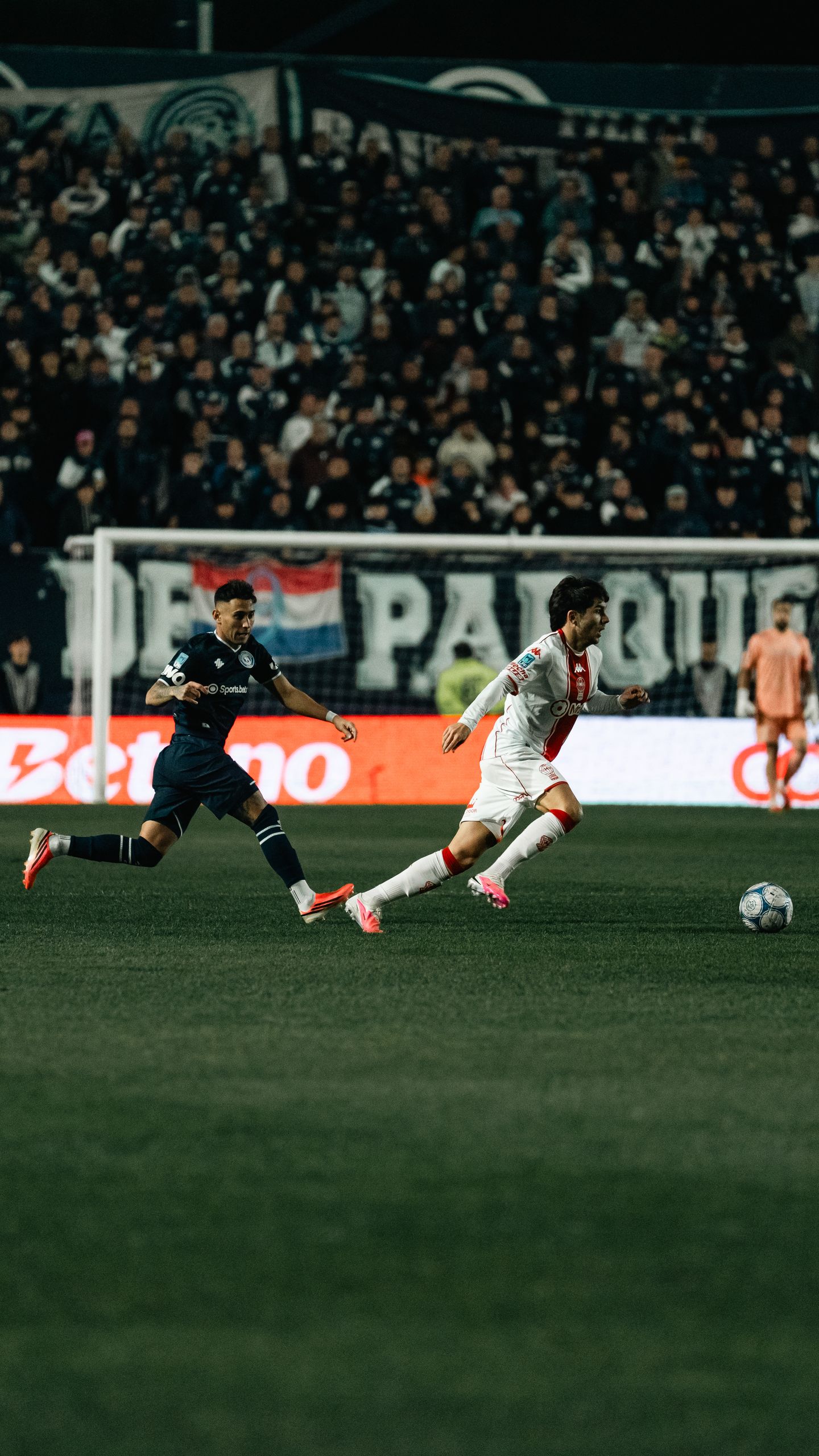 Exciting soccer game under the lights with two players in action on the field.
